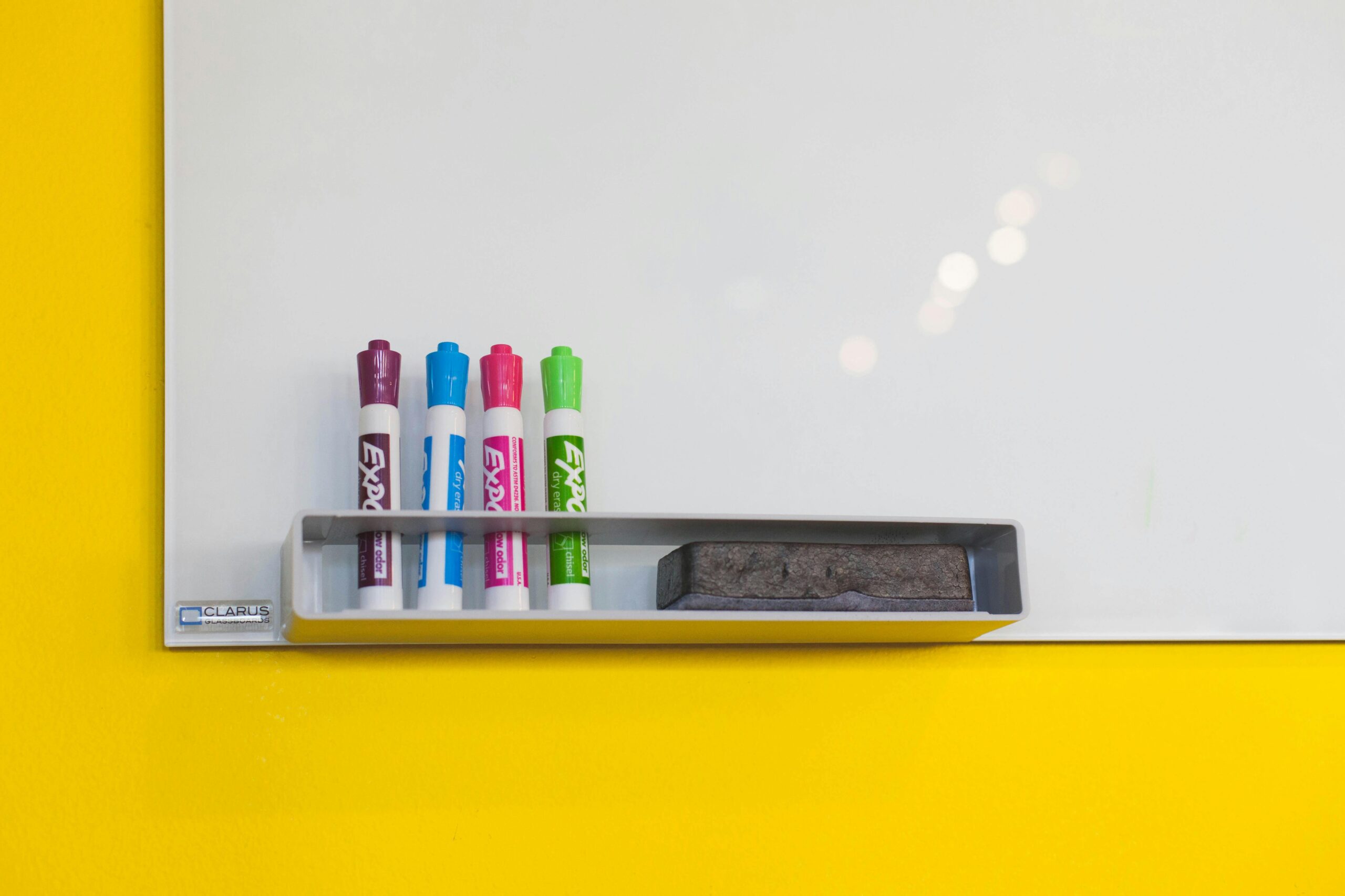 Colorful markers and eraser on a bright whiteboard in an office setting, ideal for brainstorming and planning.
